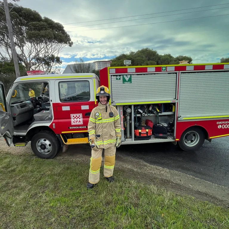 Image of a fire fighter standing in front of a fire truck.